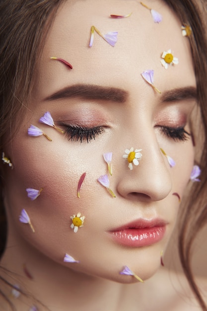 Pétales de fleurs sur le visage fille, peau femme cosmétiques