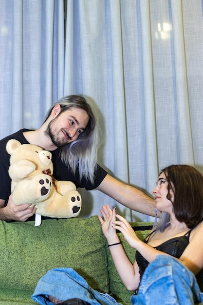 Petit ami donnant un ours en peluche à sa petite amie assise sur le canapé Fille n'aime pas ça geste de rejet