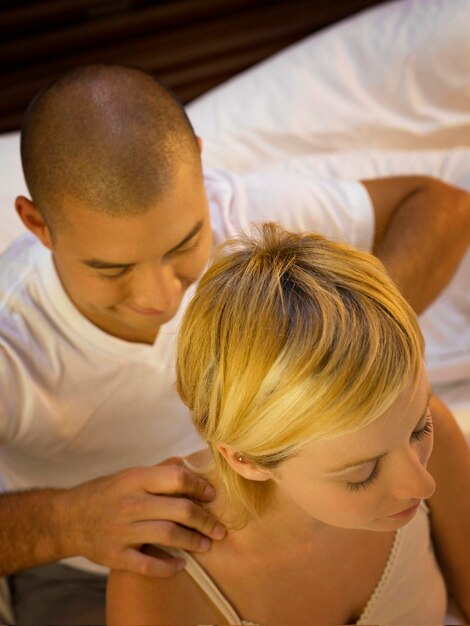 Photo un petit ami donne un massage à sa petite amie sur le lit à la maison.