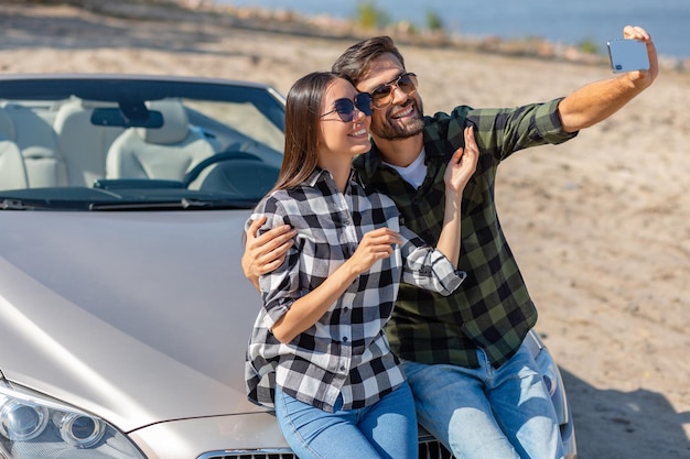 Petit ami et petite amie prenant selfie et assis sur le cabriolet