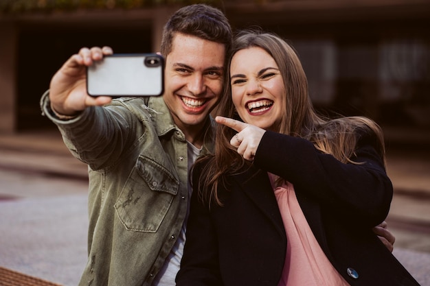 Photo un petit ami se prend un selfie avec sa petite amie sur son téléphone portable à l'extérieur.