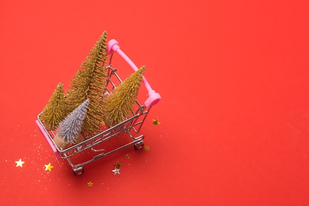 Petit arbre de Noël artificiel dans un panier sur fond rouge