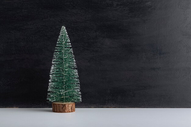 Petit arbre de Noël artificiel sur support en bois sur fond noir. Fond de nouvel an. Copier l'espace