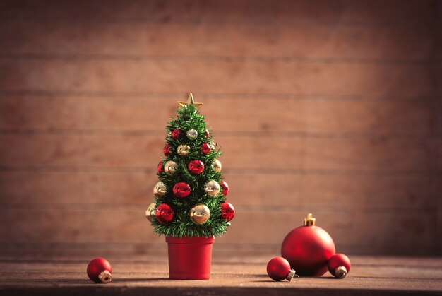 Petit arbre de Noël et boules sur table en bois et arrière-plan