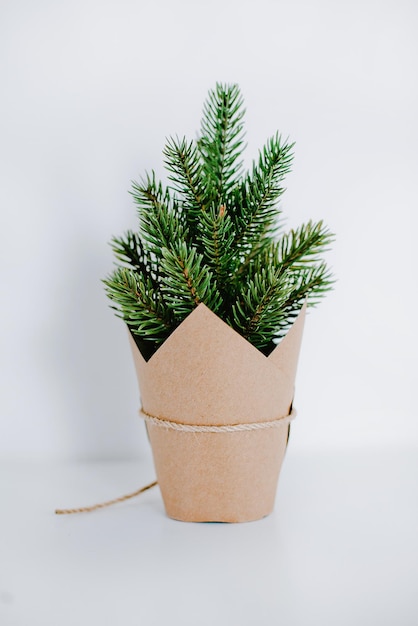 Photo petit arbre de noël enveloppé dans du papier brun sur fond blanc isolé