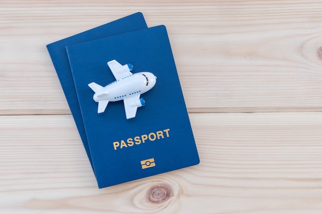 Petit avion de jouet au-dessus des passeports bleus sur un fond en bois