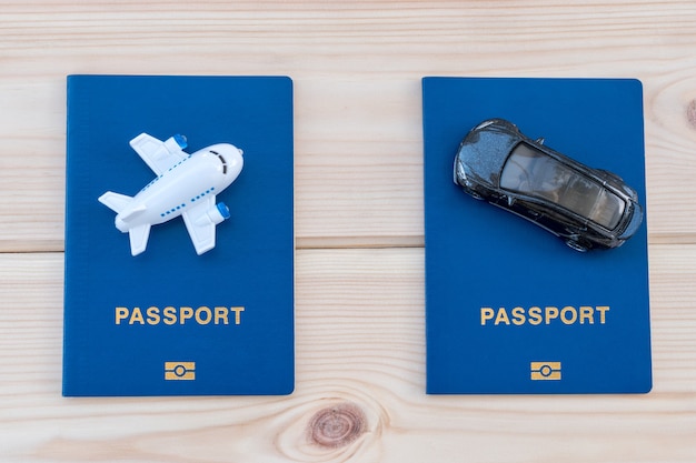 Photo petit avion jouet et petite voiture au-dessus de passeports bleus sur fond de bois.