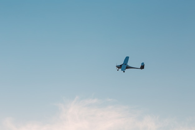 Petit avion monomoteur volant contre le ciel coucher de soleil.