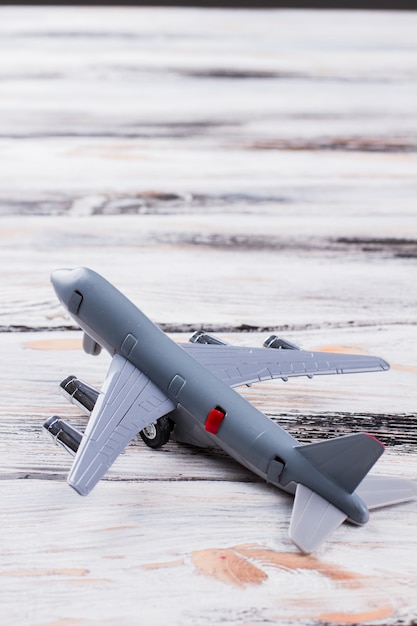 Petit avion de passagers jouet sur bois blanc. Gros plan gris avion est tourné vers la gauche.