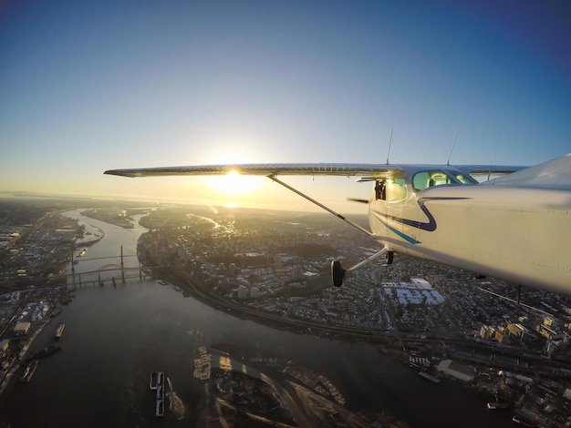 Petit avion survolant le fleuve Fraser lors d'un coucher de soleil d'hiver animé