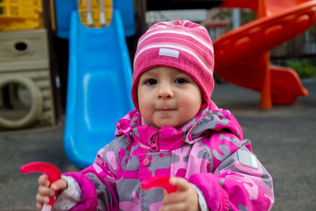 petit bambin en salopette d'hiver chaude joue sur l'aire de jeux. flou artistique