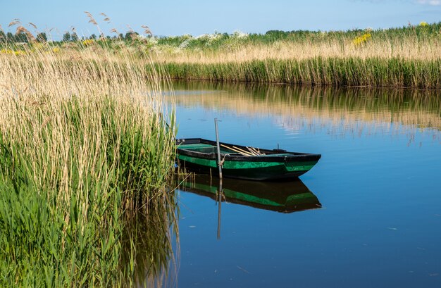 Petit bateau à rames en bois le long d'un canal au printemps