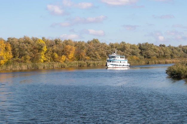 Petit bateau à vapeur blanc marchant le long d'une grande rivière d'automne