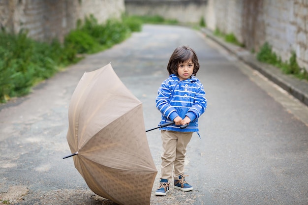 Petit beau garçon jouant avec un parapluie en plein air