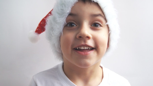 Un petit beau garçon souriant dans un chapeau de père Noël. Le concept de Joyeux Noël