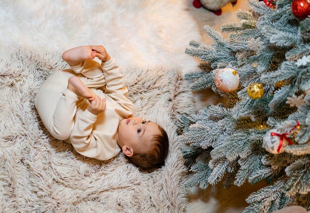 Petit bébé allongé près de l'arbre de Noël Petit enfant fête Noël à la maison Concept de Noël et du nouvel an