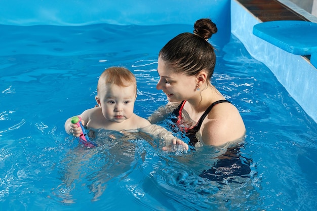 Un petit bébé apprend à nager dans la piscine avec son professeur.