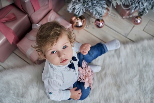 Petit bébé drôle à côté de l'arbre de Noël.