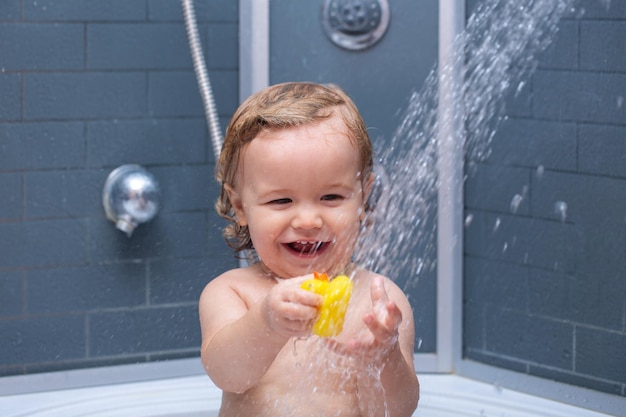 Petit bébé enfant se lave les cheveux dans le bain enfant sous la douche