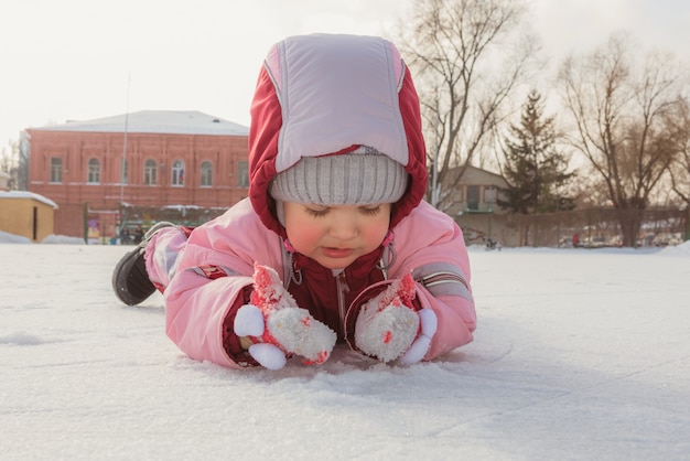 Petit bébé est allongé sur la glace en hiver