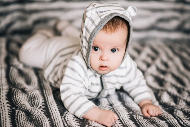 Petit bébé garçon couché sur le ventre et levant la tête pendant un moment, surpris et souriant mignon, nouveau-né