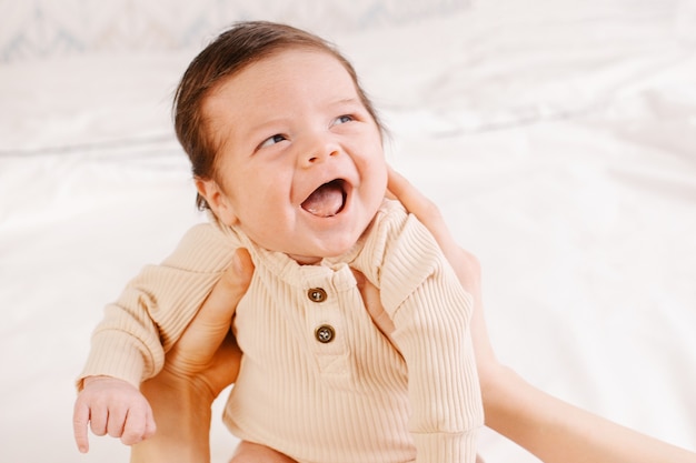 Petit bébé garçon rire sur un lit avec un drap blanc heureux