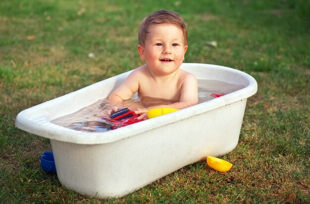 Un petit bébé heureux baigné dans le bain et jouant dans un bain avec des jouets.