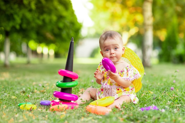 Petit bébé joue avec une pyramide sur l'herbe verte en été