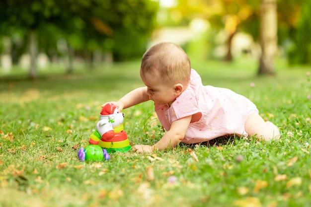 Petit bébé joue avec une pyramide sur l'herbe verte en été