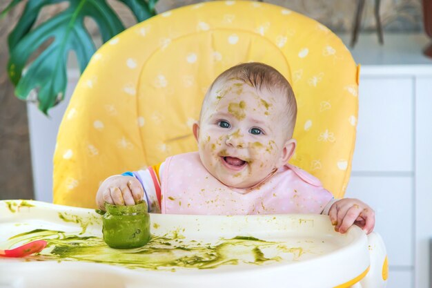 Le petit bébé mange lui-même de la purée de brocoli. Mise au point sélective. Gens.