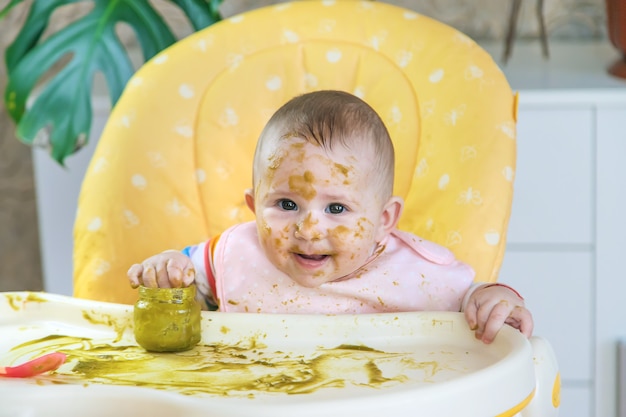 Le petit bébé mange lui-même de la purée de brocoli. Mise au point sélective. Gens.
