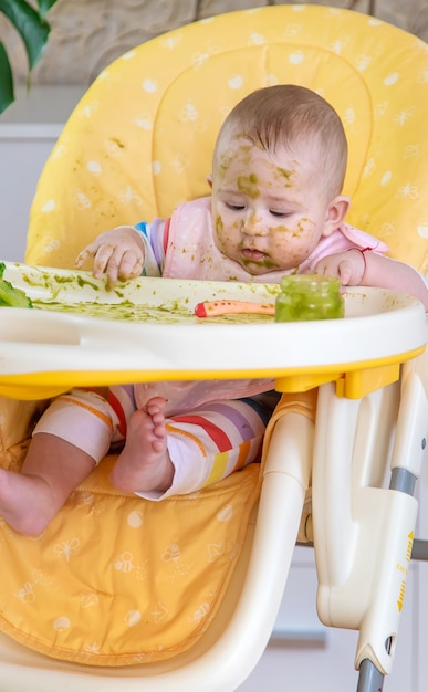 Le petit bébé mange lui-même de la purée de brocoli. Mise au point sélective. Gens.