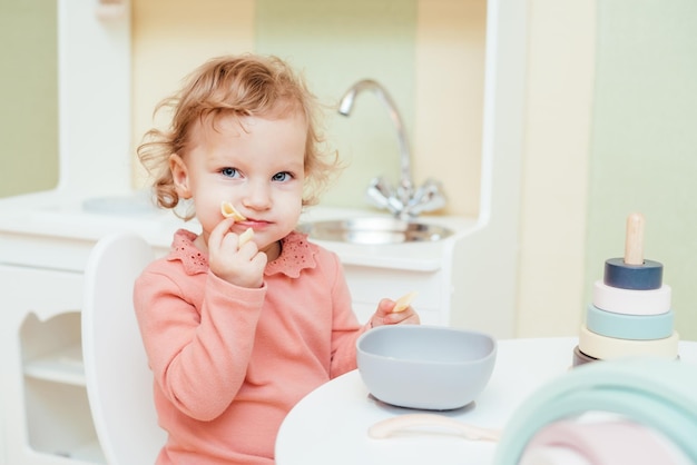 Le petit bébé mange des pâtes dans la cuisine des enfants