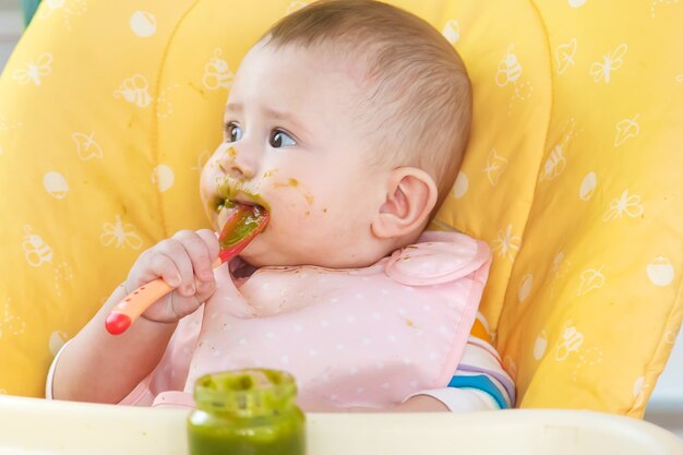 Le petit bébé mange de la purée de brocoli. Mise au point sélective. Gens.