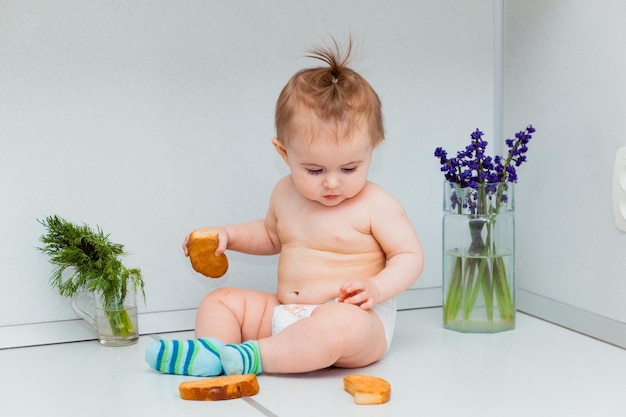 Petit bébé mignon avec des biscuits se reposant sur la table dans la cuisine