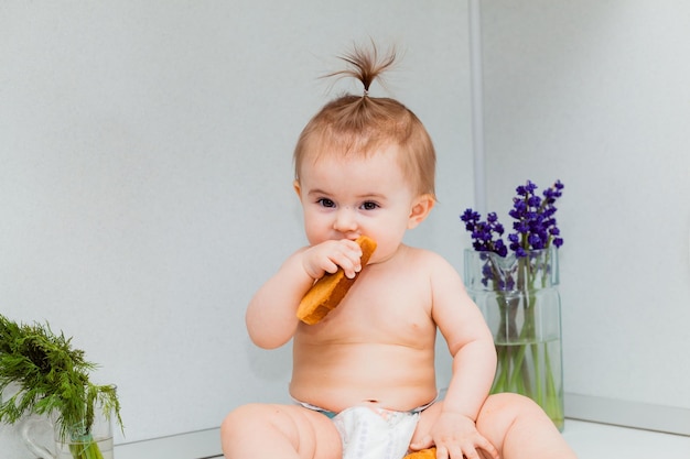 Petit bébé mignon avec des biscuits se reposant sur la table dans la cuisine