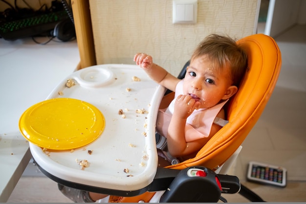 Petit bébé mignon mangeant dans la chaise de bébé