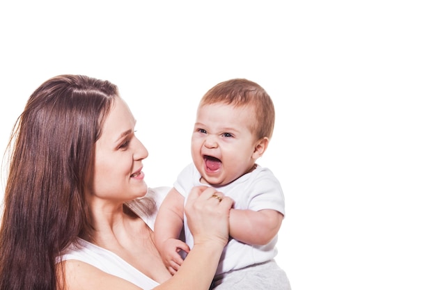 Petit bébé mignon riant tenu par les bras de sa mère, fond blanc