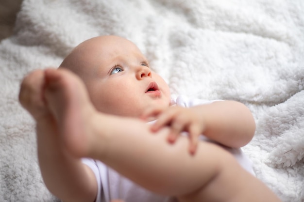 Le petit bébé mignon se trouve sur une couverture blanche