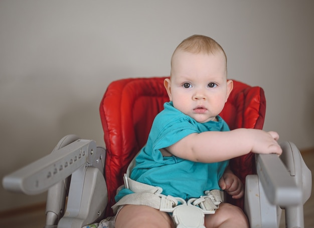 Petit bébé nouveau-né assis sur une chaise haute d'alimentation