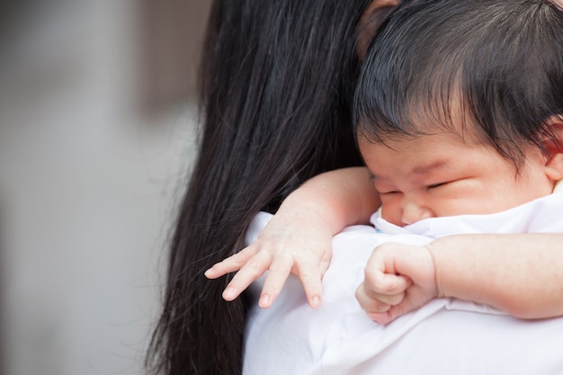 Petit bébé nouveau-né les mains sur l&#39;épaule de la mère. Maman câlins bébé avec tendresse.