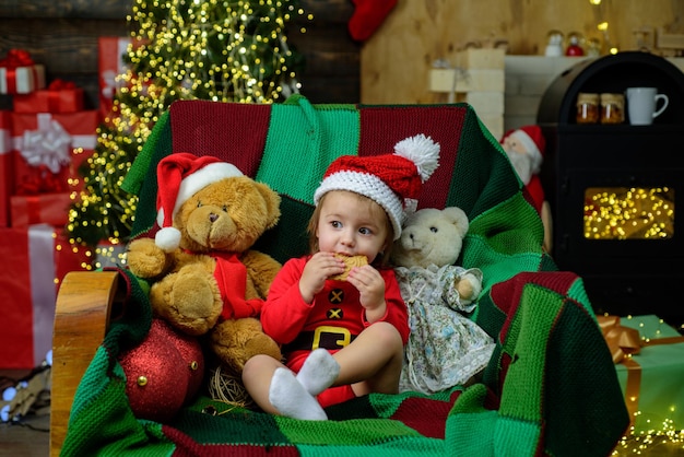 Petit bébé portant un chapeau de Noël. Petit assistant du Père Noël dans une maison de vacances.