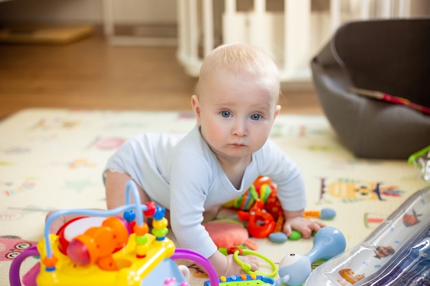 Petit bébé de six mois joue sur le sol dans des jouets