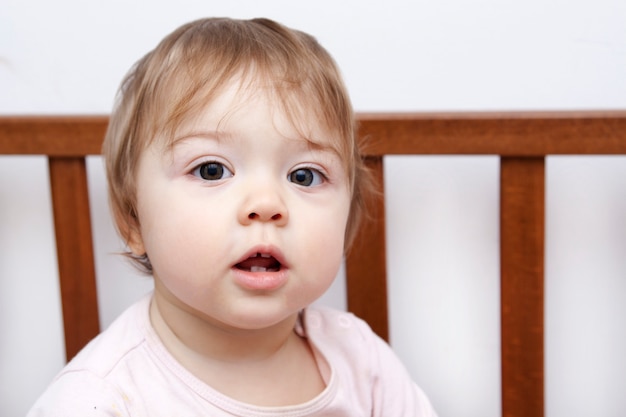 Petit bébé souriant assis dans son lit