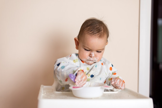 Un petit bébé en train de manger son dîner et de faire des dégâts