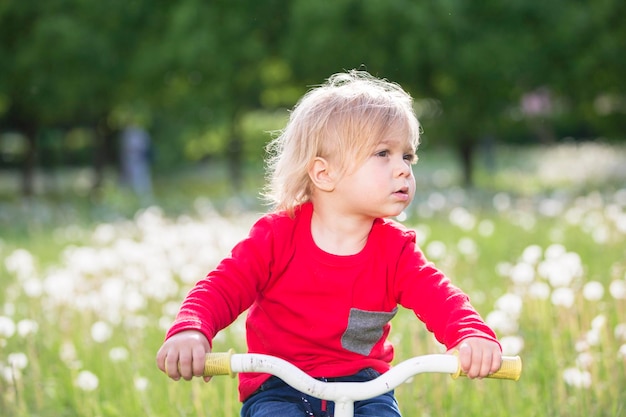 Petit bébé sur un vélo sur un pré vert