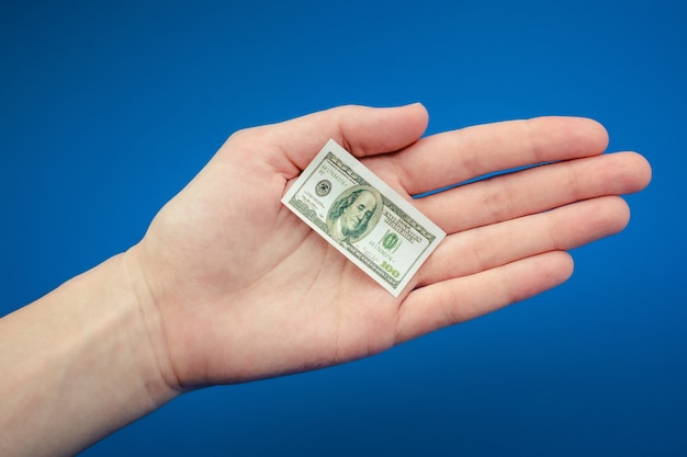 Petit billet d&#39;un dollar américain à la main sur un fond bleu