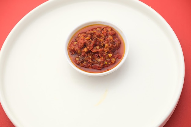 Un petit bol de sauce tomate est posé sur une assiette blanche.