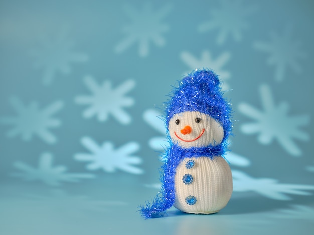 Petit bonhomme de neige sur un mur bleu avec des flocons de neige