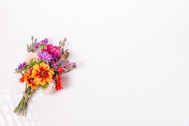 Petit bouquet d'automne d'astères roses et violettes, de dahlias orange, de rose à hanches sur fond blanc